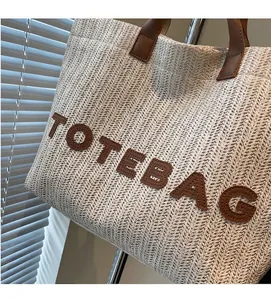 Dettaglio della trama in paglia intrecciata con manico in pelle su borsa tote beige