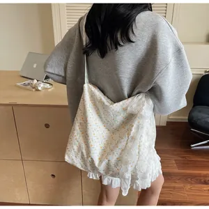 Dettaglio della borsa in pizzo bianco con stampa floreale gialla e tracolla intrecciata