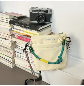 Dettaglio di una borsa a tracolla in nylon crema con doppia tracolla e fotocamera