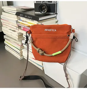 Dettaglio della borsa a tracolla in nylon arancione con logo bianco su sfondo casual