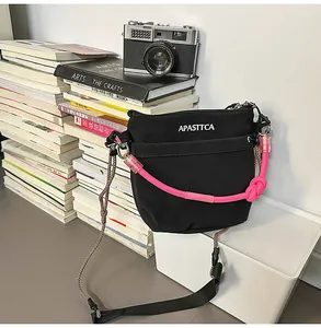 Dettaglio della borsa a tracolla in nylon con manico in corda rosa e scritta