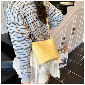 Dettaglio di una borsa a secchiello in pelle intrecciata gialla con trama a trama larga