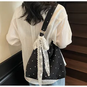 Dettaglio della borsa shopper floreale con un grande fiocco in pizzo bianco sulla tracolla