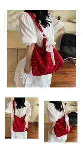 Dettaglio borsa tote rossa floreale con fiocco in pizzo bianco e tracolla regolabile