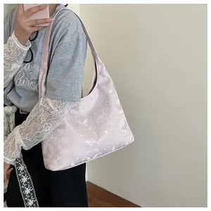 Detail of light pink shoulder bag featuring floral butterfly jacquard and satin finish