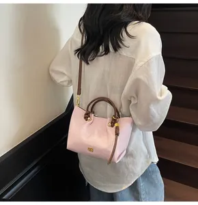 Borsa a mano in pelle martellata rosa con manici marroni in un contesto di stile urbano