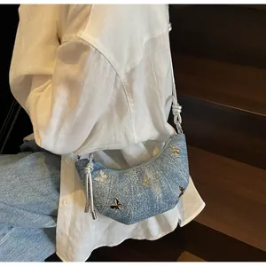 Borsa a mezzaluna in denim blu con farfalle d'argento indossata da modella