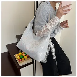 Close-up of light blue tote bag with pink butterfly patterns and white lace shoulder strap