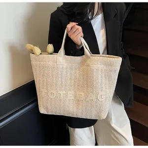 Détail d'un grand sac cabas en paille tissée avec lettrage TOTEBAG en relief et fleurs
