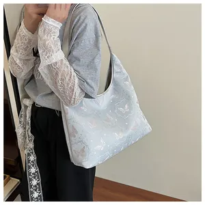Shoulder bag size demonstration on model featuring blue leather and pink butterfly pattern