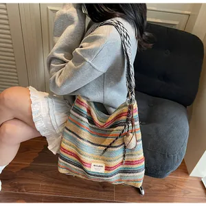 Dettaglio della borsa tote in paglia colorata con tracolla geometrica e pompon