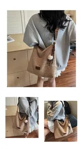 Dettaglio borsa tote intrecciata marrone con tracolla geometrica e ciondolo a pompon