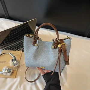 Borsa tote in denim azzurro con manici in pelle marrone e dettagli in metallo oro