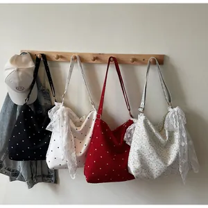 Dettaglio di borse tote in tela con bordo in pizzo e vari motivi a pois colorati