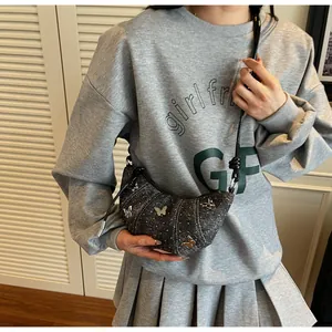 Dettaglio borsa a mezzaluna grigio scuro con farfalle metalliche e trama in denim chic