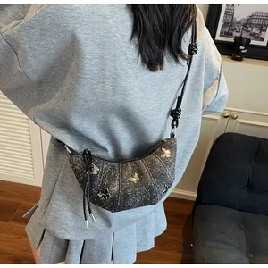 Dettaglio borsa a mezzaluna grigio scuro glitterata con farfalle argentate indossata