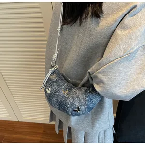 Dettaglio borsa a mezzaluna in denim con farfalle metalliche e tracolla sottile a corda