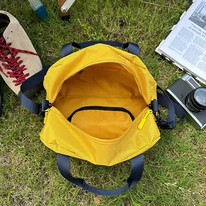 Outdoor yellow nylon crossbody tote bag with inner zipper pocket on green grass