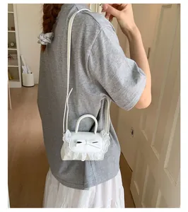 Mini borsa a tracolla bianca con pizzo e fiocco indossata da modella in casa accogliente
