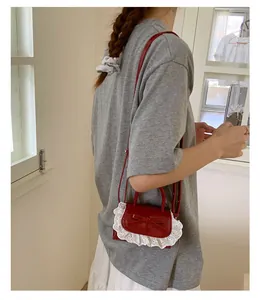 Dettaglio della mini borsa rossa con bordo in pizzo bianco e fiocco su un modello