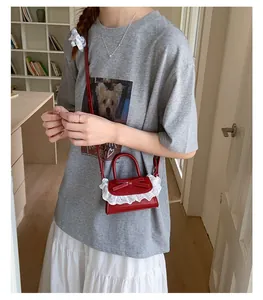 Dettaglio mini borsa a tracolla rossa in ecopelle con pizzo bianco e fiocco decorativo