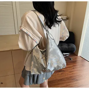 Close-up of silver metallic tote bag with chain strap and butterfly tassel detail