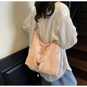 Close-up of pink silk-texture tote bag with butterfly charm and metal chain detail