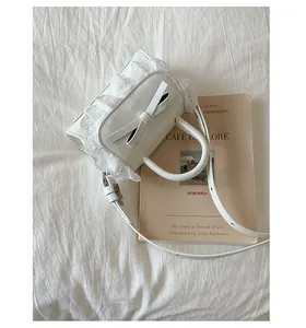 Dettaglio di una borsa in pizzo bianco con un fiocco delicato e bordi floreali ricamati
