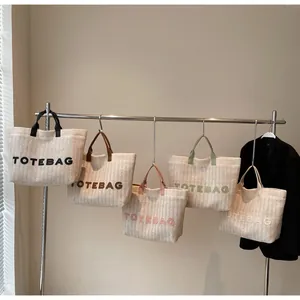 Groupe de cinq sacs fourre-tout tissés avec broderies colorées suspendus sur un portant