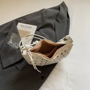 Borsa croissant bianca in pelle lucida con borchie argentate e tracolla annodata
