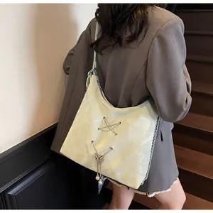 Detail of mint green tote bag with metal eyelets and pearl butterfly pendant on shoulder