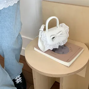 Elegante borsa in pizzo bianco con fiocco e tracolla su supporto di legno, 80-100 car.