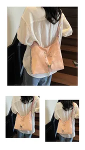 Detail of pink hobo bag with metal eyelets, lace-up design, and pearl butterfly charms