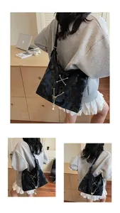 Detail of black glossy tote bag featuring metal butterfly charm and X-cross lacing