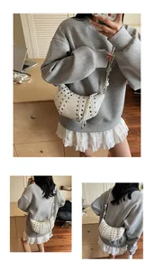 Dettaglio borsa a mezzaluna bianca con borchie argentate e tracolla con nodo moda