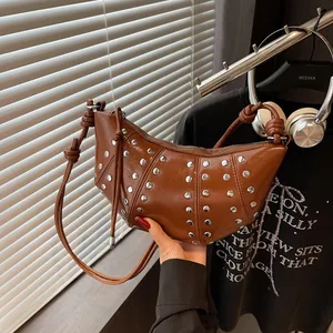 Borsa a mezzaluna in pelle marrone con borchie argentate e forma a croissant minimalista