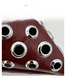 Macro shot of dark red textured leather bucket bag with silver metal eyelet studs