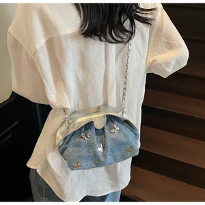 Detail of light blue denim bucket bag with silver butterfly and chain strap on a model
