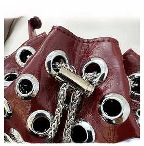 Close-up of wine red patent leather bucket bag with silver metal eyelets and drawstring lock