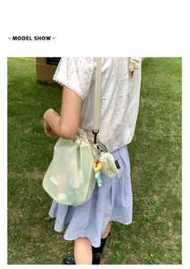 Detail der hellgrünen Netz-Beuteltasche mit Kordelzug und gelbem Tieranhänger auf Rasen