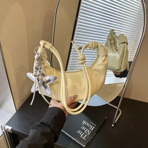 Chic cream-colored crescent shoulder bag with silver star pendant and knotted strap