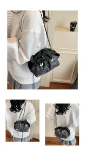 Detail of dark grey textured bucket bag featuring silver butterfly appliques and chain strap