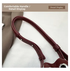 Detail view of burgundy studded shoulder strap with silver rivets and metal grommets