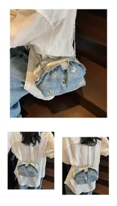 Detail of blue denim bucket bag with metallic butterfly accents and silver chain strap