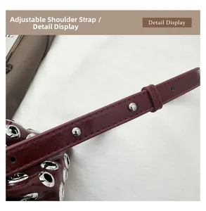 Detail display of the adjustable shoulder strap on a burgundy punk studded bucket bag