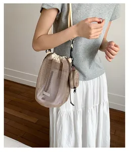 Detailansicht der beigefarbenen Mesh-Beuteltasche mit kleiner Münztasche und verstellbarem Gurt