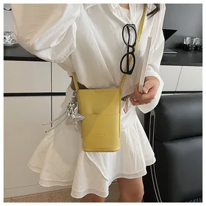Detail of yellow lychee leather mini crossbody bag with silver star charm and front pocket