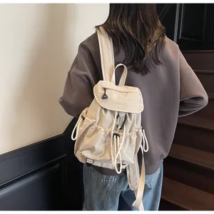 Detail view of cream drawstring backpack showing side pocket and functional black buckle