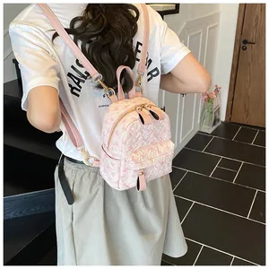 Detailed back view of a pink embossed floral backpack worn by a model in casual setting