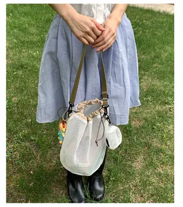 Detail der weißen Netztasche mit Kordelzug und khakifarbenem Segeltuch-Schultergurt